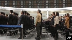 Nhân viên thị trường chứng khoán Hàn Quốc chào cờ trong lễ khai mạc buổi giao dịch đầu tiên của năm 2013 tại Seoul.