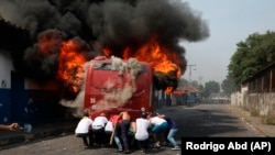 Демонстранти штовхають підпалений під час сутичок з Національною гвардією Венесуели автобус в Урені, Венесуела, біля кордону з Колубмією. 23 лютого 2019 року.