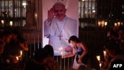 Jemaat meletakkan lilin yang menyala di dekat foto Paus Fransiskus selama acara doa bersama untuk kesehatannya di Buenos Aires pada 7 Maret 2025. (Foto: AFP)