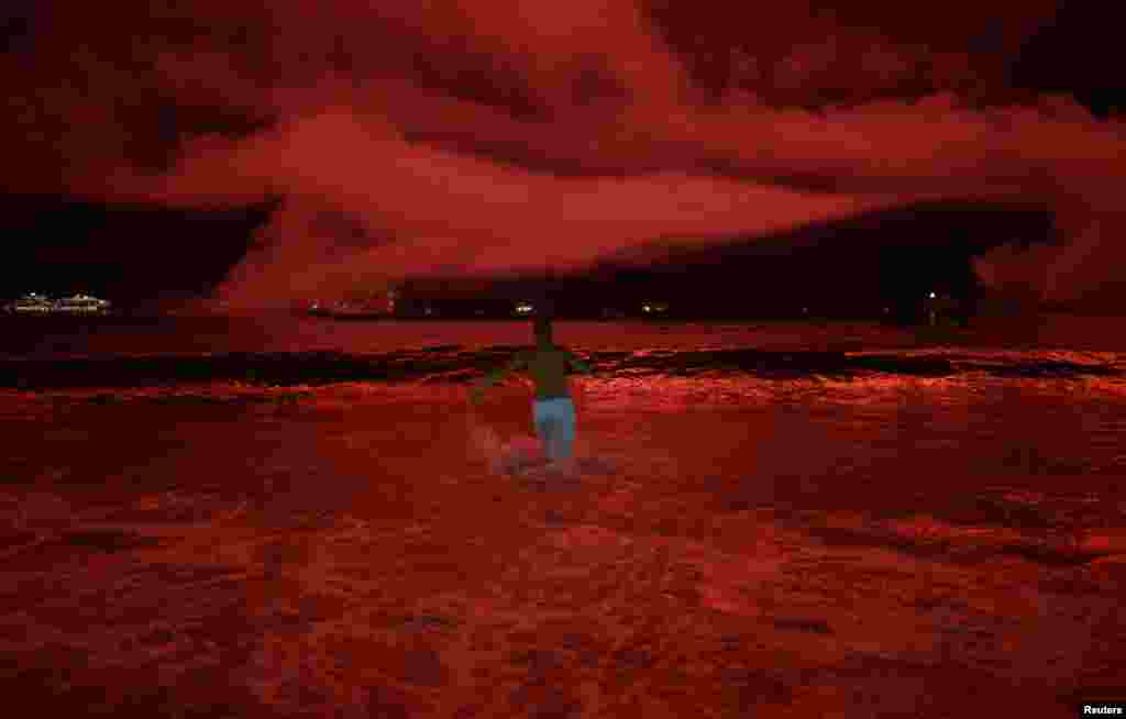 2018年1月1日在巴西里约热内卢举行的新年庆祝活动中,科帕卡巴纳海滩烟花怒放,映红天空和海面,一名男子跑入海里。