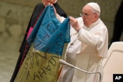 罗马天主教教宗方济各亲吻一面从布查镇送给他的乌克兰国旗,并强烈谴责“布查大屠杀”。(2022年4月6日)