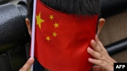 上海外滩的一个小男孩手拿一面中国国旗参加庆祝中共建政75周年的活动。(2024年10月1日)