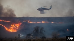 2025年1月22日,一架消防直升机在美加州洛杉矶县西北社区卡斯泰克上空洒水以扑灭休斯大火。