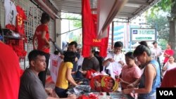 缅甸仰光民盟总部门外,民盟的拥护者们正在抢购印有昂山素季及民盟旗帜的纪念品。(美国之音朱诺拍摄)