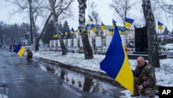 资料照片:2025年2月5日,在乌克兰波尔塔瓦州季卡尼卡,为2月1日因俄罗斯袭击波尔塔瓦居民楼而丧生的包括儿童在内的四名乌克兰人举行的葬礼期间,乌克兰军人单膝跪地,表示哀悼。