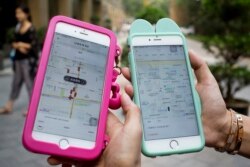 Wanita sedang memegang ponsel cerdas yang memperlihatkan aplikasi Uber di Beijing, 1 Agustus 2016. (Foto: AP)