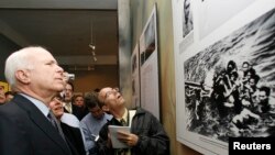 Thượng nghị sĩ Mỹ John McCain nhìn bức ảnh lúc ông bị bắt trên hồ Trúc Bạch trong chuyến thăm nhà tù Hỏa Lò tại Hà Nội hồi tháng 4, 2009.