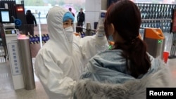 2020年1月24日农历新年前夕,穿着防护服的工作人员检查(到达与武汉北部接壤的)咸宁市乘客的体温。