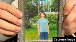 吾萨尔·瓦伊提拿着他19岁妹妹卡米莱·瓦依提的照片 (由吾萨尔·瓦伊提提供)