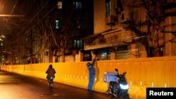 一名快递员在上海封城后给一户人家在围栏上递送食物。(2022年3月31日)