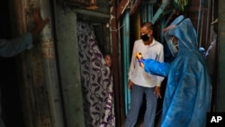 资料照片:一位医生在孟买的贫民窟为一个女孩量体温,防止新冠病毒蔓延。