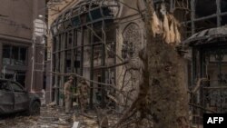 Чоловіки у військовій формі біля пошкодженої будівлі на місці російського ракетного обстрілу в Києві 20 грудня 2024 року. Roman PILIPEY/AFP