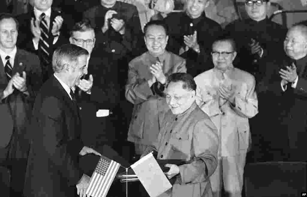 1979年8月28日,美国副总统蒙代尔和中国副总理邓小平在两国文化和水电协议书签署后,交换协议文本。前排鼓掌者有中国总理华国锋(中)、美国驻华大使伦纳德•伍德科克(华国锋左侧)和中国外交部长黄华(华国锋右侧)。中国改革开放40周年展览会没有提到为改革开放做出重要贡献的华国锋。