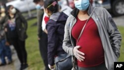 资料照片:一名孕妇在马塞诸塞州一座教堂前排队领取食品(2020年5月7日)