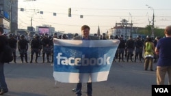 2012年5月6日普京再次就任总统前夕,莫斯科市中心爆发大规模反政府示威,一名示威者手举脸书旗帜。(美国之音白桦拍摄)