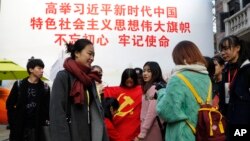 一群大学生手举中共党旗在写有“习近平语录”的宣传板前合影。(2017年11月19日)