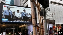 香港街头电视新闻屏幕显示检察人员把薄熙来押上法庭受审