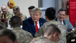 2019年11月28日星期四,特朗普总统在共和党参议员约翰·巴拉索陪同下共进晚餐时微笑。他在当天的感恩节突防阿富汗巴格拉姆空军基地。 (美联社照片)