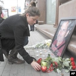 在莫斯科市中心,一位妇女把一个苹果放在一家苹果电脑商店外的乔布斯的画像边
