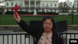 基督徒王春艳举着十字架站在白宫前面(2016年4月2日,对华援助协会网站图片)