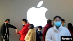 资料照:戴着口罩的人们排队等候测量体温进入一家上海的苹果商店。(2020年2月21日)