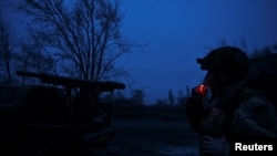 在扎波罗热州前线,一名州警特别步枪营炮兵队成员在向俄军开火前在多管火箭系统边抽烟。(2024年12月25日)