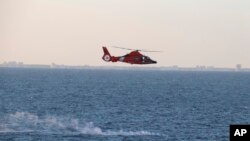 美国海军提供的图片显示美国海岸警卫队直升机在回收中国高空侦察气球残骸行动期间飞过碎片散落区。(2023年2月4日)