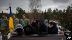 在乌克兰伊尔平举行的葬礼上,2023年1月17日在巴赫穆特阵亡的乌克兰军人爱德华·斯特劳斯的亲人站在他的灵柩边。(2023年2月6日)