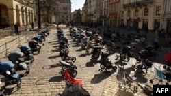 乌克兰利沃夫市议会外摆放着109个空空的婴儿推车和摇篮,象征俄军入侵乌克兰迄今被夺去生命的109名儿童。(2022年3月18日)