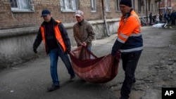 2022年3月23日,在乌克兰基辅,邻居们从被炮击的公寓里搬出被打碎的窗户玻璃碎片。(美联社)