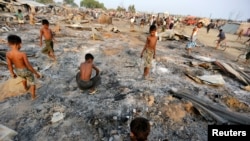 2016年5月3日,在缅甸西部实兑附近的诺开邦,大火摧毁了流离失所的罗欣亚穆斯林的临时住所,一群男童正在烧毁的住房废墟中寻找有用物品。