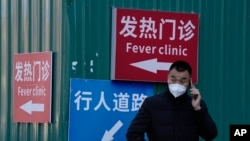 一名男子站在街头打电话。他身后的红色指示牌上写着”发热门诊“。自从中国政府出人意料地突然放宽了封控措施之后,各地的感染人数不断增加,使原本就贫乏的医疗资源面临更沉重的压力。