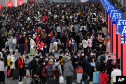 “春运”在如同海啸般蔓延的新冠感染爆发中拉开帷幕。广东深圳南站大厅内,旅客们人们带着口罩和行李,熙熙攘攘挤满大厅,等待买票和登车。本照片由新华社发布,美联社提供。