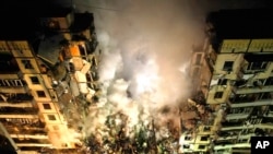 2023年1月14日,在乌克兰东南部城市第聂伯罗,一枚俄罗斯火箭击中一幢多层建筑,许多人被埋在废墟下,急救人员正在清理废墟。