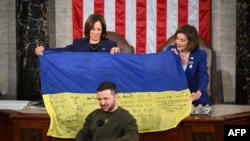 在乌克兰总统泽连斯基对国会联席会议发表演说之际，美国副总统哈里斯和众议院议长佩洛西展示着泽连斯基送给国会的有前线乌军签名的乌克兰旗帜。(2022年2月21日)