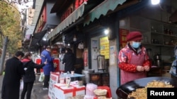 中国政府放宽清零政策后，湖北武汉街头人们在小摊前排队购物。（2022年12月10日）