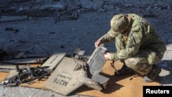 资料照片:一名警察在哈尔科夫遭到俄罗斯空袭的燃油储存设施现场检查一架据信是伊朗制造的“沙希德-136”自杀式无人机的残骸。(2022年10月6日)