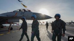 中国海军第二艘、也是第一艘完全由本国建造的002型山东号航母。照片显示山东号停泊在三亚军港,飞行员走在甲板上。-新华社照片