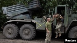 在乌南尼古拉耶夫地区的前线附近,一名乌克兰女军人在丈夫兼战友的帮助下跳下BM21“冰雹”多管火箭发射车。(2022年9月16日)