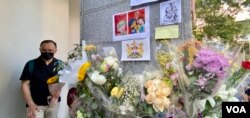 英国驻港总领事馆大楼的支柱上贴满悼念女皇的鲜花和心意卡,有手持鲜花排队等候进入领事馆签署吊唁册的市民神情哀伤 (美国之音/汤慧云)
