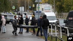 2022年9月26日,在俄罗斯伊热夫斯克市第88学校发生枪击事件的现场,殡仪人员抬着一具遇难者遗体。