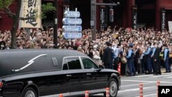 日本前首相安倍晋三的葬礼举行后,运载安倍棺木的灵车离开寺庙,日本民众路旁送行。(2022年7月12日)