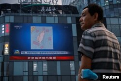 北京市民在观看街头电子屏幕上官媒央视播放的中国军队在台湾附近举行实弹军演的报道。(2022年8月4日)