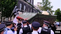 2022年6月4日,伦敦警察在中国驻英国大使馆外阻止示威者抬着的纸扎坦克走近大使馆范围。 (美国之音郑乐捷)