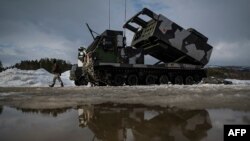 资料照片:在挪威举行的一次国际军演期间,一名军人走过一部M270多管火箭发射系统。(2022年3月22日)