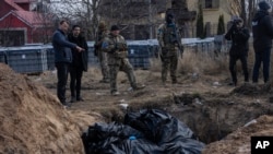 人们站在基辅郊外布查镇的一处乱葬坑边。(2022年4月4日)