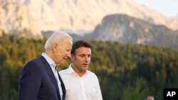 资料:2022年6月26日,美国总统拜登和法国总统马克龙在德国出席七国集团峰会时交谈。(美联社照片)