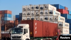 2019 年12月12日,一名工人在中国天津港附近的物流中心驾驶一辆载有集装箱的卡车。图片来源:路透社