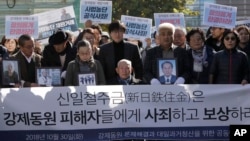 二战期间被日本钢铁公司新日铁住金强制劳役的李俊石(中坐者), 在首尔最高法院外。他身前的横幅写着:“新日铁住金应赔偿并向强迫劳动的受害者道歉”。(2018年10月30日)