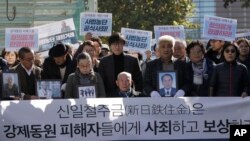 二战期间被日本钢铁公司新日铁住金强制劳役的李春希(中坐者), 2018年10月30日在首尔最高法院外。他身前的横幅写着:“新日铁住金应赔偿并向强迫劳动的受害者道歉”。
